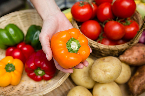 Close-up of woman holding fresh bell pepper at vegetable stall