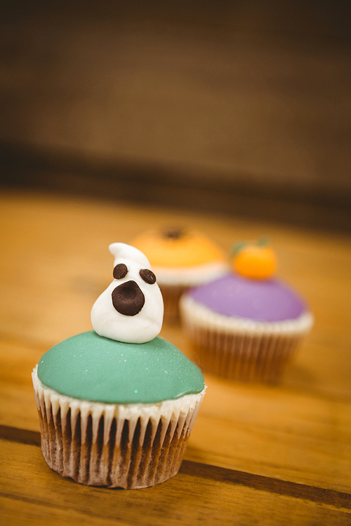 Close up of cup cake with ghost on wooden table during Halloween