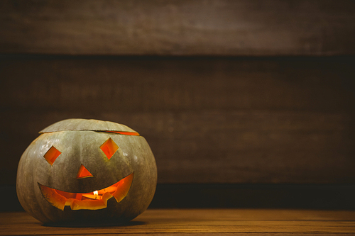 Illuminated jack o lantern on wooden table during Halloween