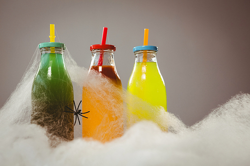 Close up of cotton candy by colorful drinks and spider over white background
