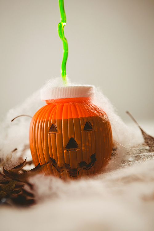 Close up of drink in jack o lantern container over white background
