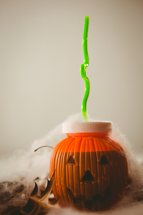 Close up of drink in jack o lantern container against white background