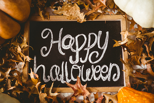 overhead view of happy halloween text on slate amidst  leaves