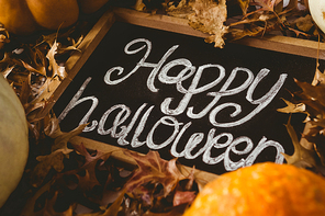 high angle view of happy halloween text on slate amidst  leaves