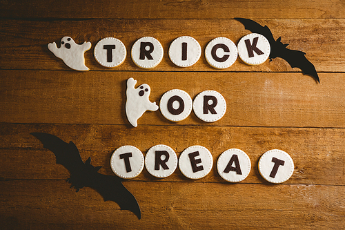 High angle view of cookies with trick or treat text by spooky decorations on table