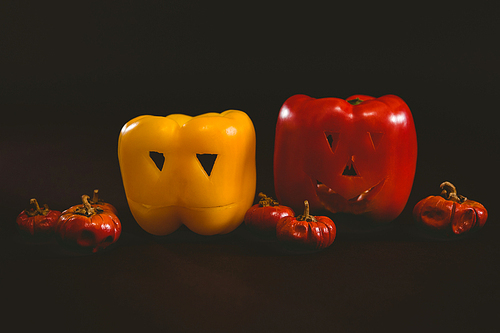 Close up of carved bell peppers with small pumpkins over white background