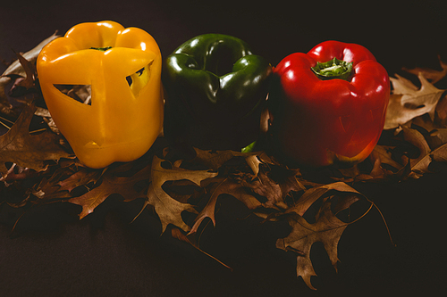 high angle view of carved bell peppers with  leaves over black background