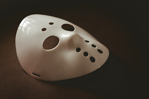 High angle view of evil mask over brown background
