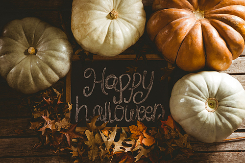 overhead view of happy halloween text on slate by pumpkins amidst  leaves