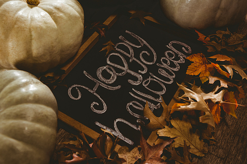 high angle view of happy halloween text on slate with pumpkins and  leaves