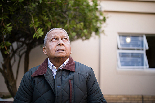 Retired senior man looking up against nursing home