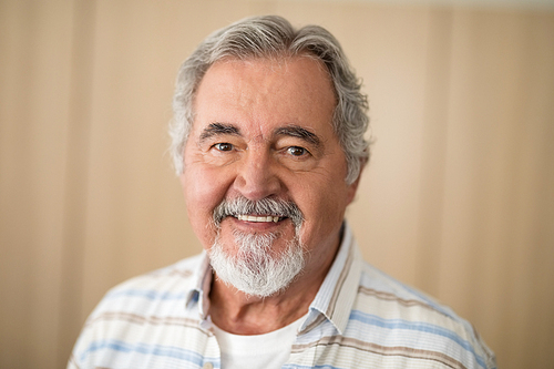 Close-up portrait of senior man against wall at retirement home