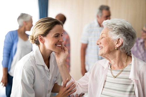 Senior woman touching smiling female doctor at retirement home