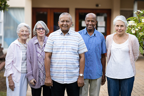 Portrait of smiling seniors standing against retirement home