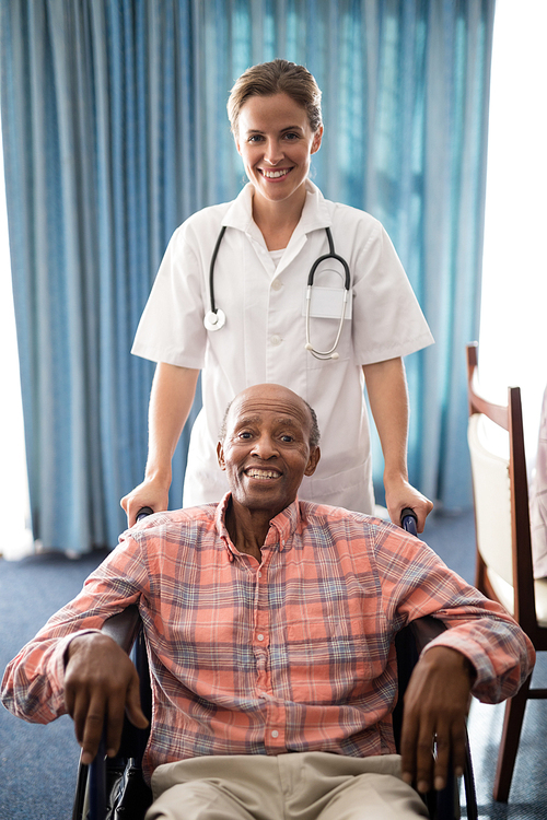 portrait of smiling female doctor standing with disabled senior man sitting on . at retirement home