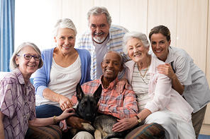 Portrait of smiling doctor and senior friends with dog at nursing home
