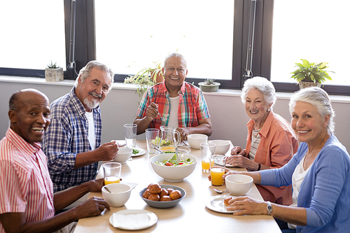 Portrait of senior people having breakfast at table in nursing home