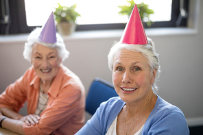 Portrait of smiling senior friends wearing party hats at nursing home