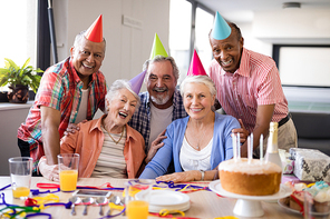 Portrait of cheerful senior people wearing party hats celebrating birthday at nursing home