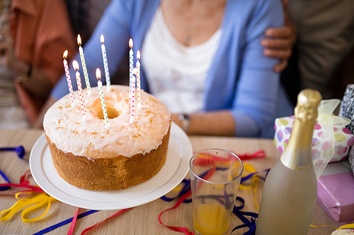Close-up of candles on birthday cake with senior people in background
