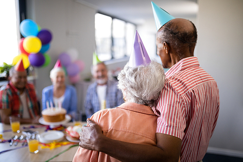 Rear view of senior couple looking at friends sitting by table during birthday celebration