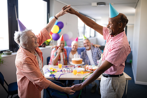 Senior couple making frame against friends by holding hands while enjoying in birthday party