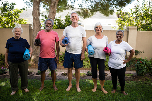 Full length of multi-ethnic senior people carrying exercise mats while standing at park