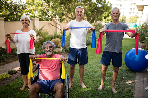 Portrait of senior couple holding multi colored ribbons while exercising at park