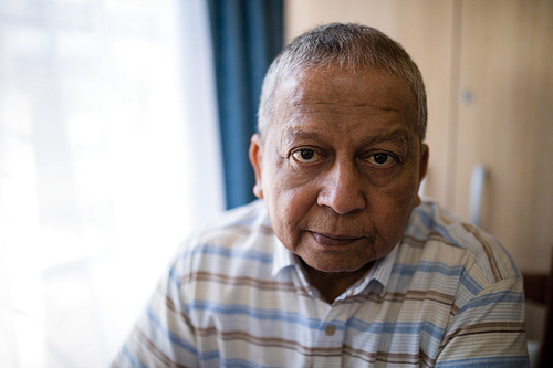 Portrait of serious senior man by window at nursing home