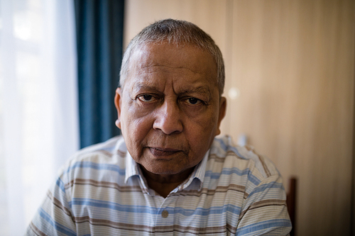 Portrait of senior man sitting by window at nursing home