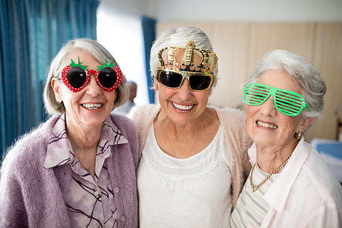 Portrait of smiling senior women wearing novelty glasses at nursing home