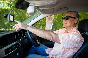Senior man using mobile while driving car