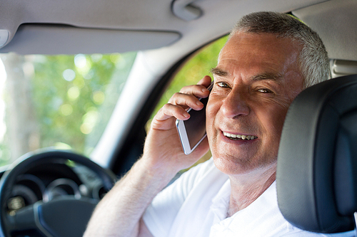 Portrait of smiling senior man talking on phone in car