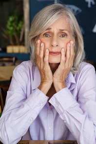 Portrait of worried senior woman at table in cafe shop