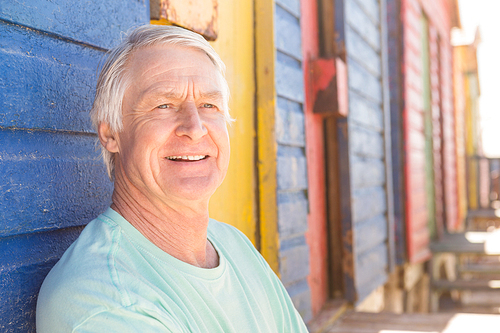 Close up of smiling man looking away against beach hut