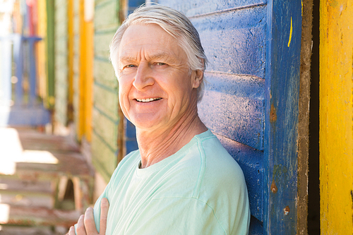 Portrait of smiling senior man standing by wall at beach