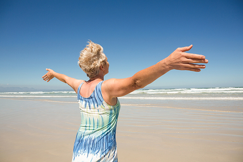 Rear view of woman with arms outstretched standing against clear sky