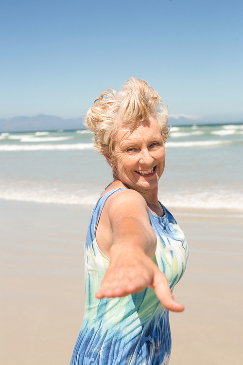 Portrait of cheerful senior woman standing against clear sky at beach