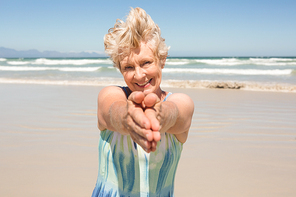 Portrait of happy senior  woman standing against clear sky at beach
