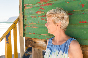 Close up of woman looking away while standing against wall at beach