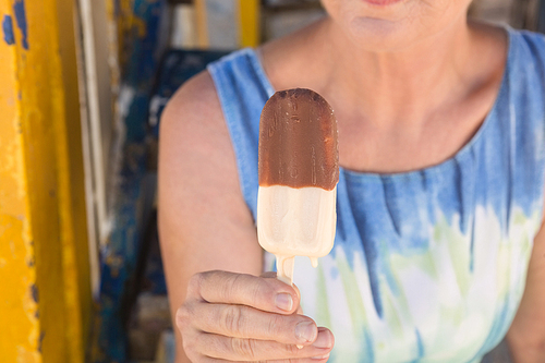 Midsection of woman holding ice cream while sitting at beach hut