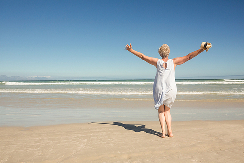 Rear view of woman standing on sand against clear sky at beach