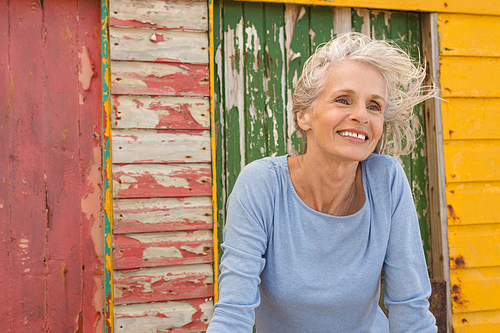 Close up of happy woman looking away while standing against beach hut