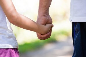 Close-up of grandfather holding his granddaughter hand in the forest