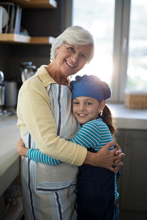Smiling grandmother and granddaughter embracing in the kitchen