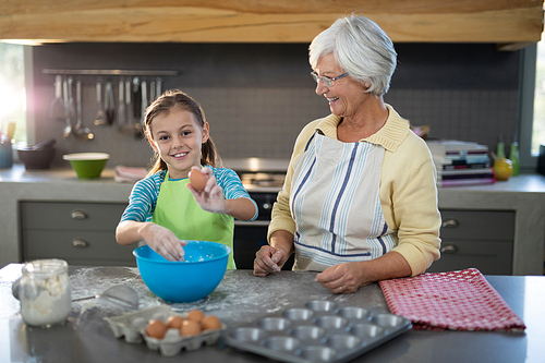Granddaughter holding eggs and grandmother smiling in the kitchen