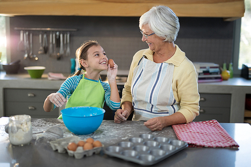 Granddaughter showing eggs to grandmother and smiling in the kitchen