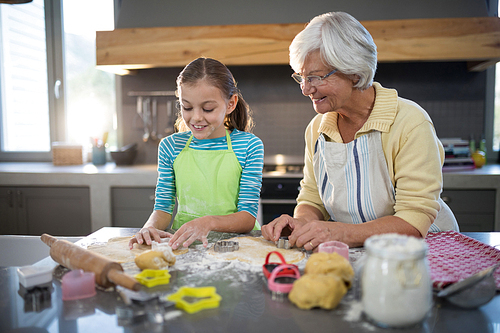Grandmother and granddaughter cutting dough with a cookie cutter in the kitchen