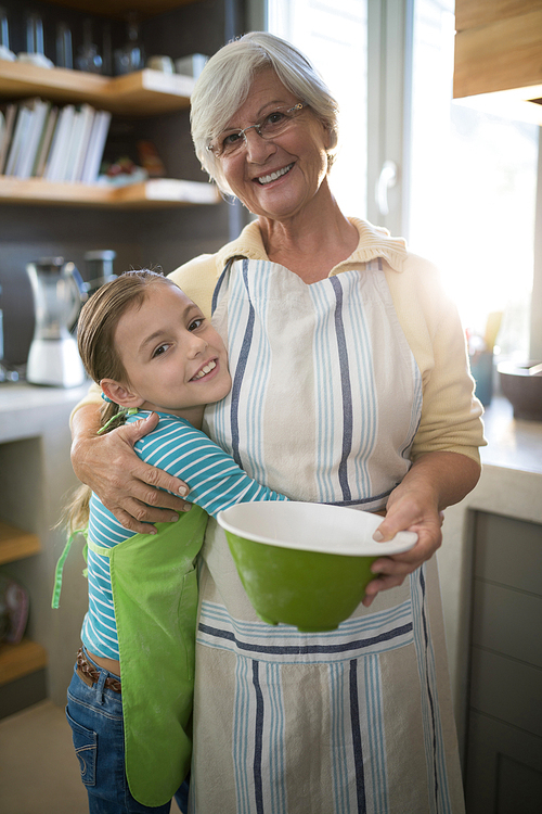 Smiling grandmother and granddaughter embracing in the kitchen