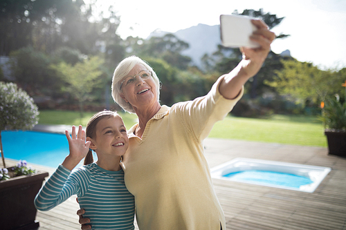 Smiling granddaughter and grandmother taking a selfie near the pool